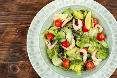 Téléchargez les photos : Salade asiatique de brocoli aux crevettes, tomates cerise et légumes verts sur fond de bois rustique. - en image libre de droit