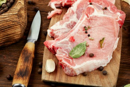 Photo for Raw uncooked pork steak on the bone on a rustic wooden table. Fresh meat. Rustic style. - Royalty Free Image