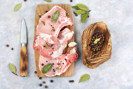 Foto de Filete de cerdo crudo en especias sobre una tabla de madera. - Imagen libre de derechos