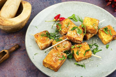 Photo for Skewers with roasted soy cheese tofu on the plate. Vegetarian grilling. - Royalty Free Image
