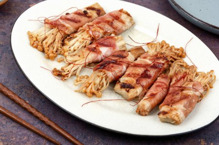 Photo for Enoki mushrooms roasted in bacon on plate - Royalty Free Image