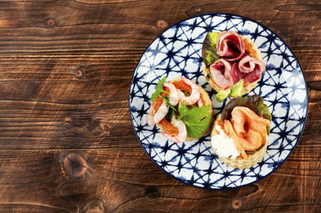 Photo for Appetizing tartlets with smoked salmon fish, shrimp and bacon. Space for text. - Royalty Free Image