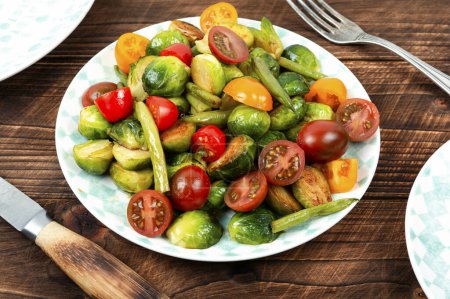 Photo for Homemade salad of fried brussels sprouts, tomato and green bush beans on a rustic wooden table. - Royalty Free Image