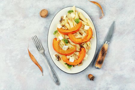 Photo for Pasta with baked pumpkins and walnuts in a ceramic plate. Seasonal autumn food. Flat lay. - Royalty Free Image