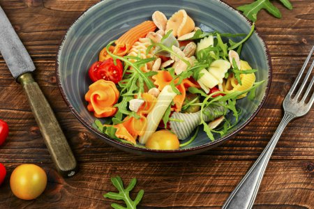 Téléchargez les photos : Salade aux tomates fraîches, herbes et pâtes dans une assiette sur une table en bois sombre . - en image libre de droit