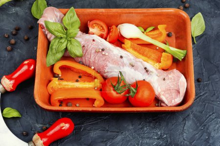 Photo for Fresh roasting meat in a baking dish with peppers, tomatoes and herbs. - Royalty Free Image