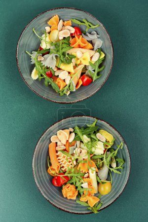 Téléchargez les photos : Un bol avec une salade de pâtes traditionnelles avec des tomates fraîches et des herbes. Vue de dessus, vue aérienne. - en image libre de droit