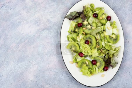 Téléchargez les photos : Salade de kiwi, légumes verts, baies et pignons de pin. Régime alimentaire Keto. Espace de copie - en image libre de droit
