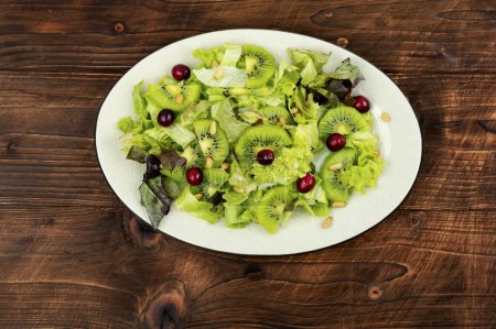 Photo for Fresh salad of kiwi, leafy greens, berries and pine nuts on the table. Clean eating. - Royalty Free Image