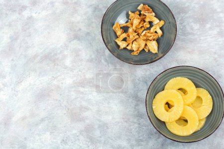 Téléchargez les photos : Ananas secs et frais dans des bols. Ananas aux bonbons, fruits confits. Espace de copie. - en image libre de droit