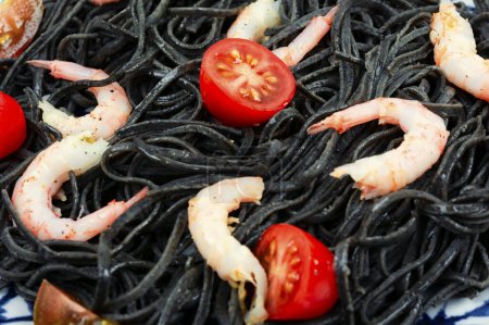 Photo for Vegan black bean spaghetti with shrimp and tomatoes. Cooked black pasta spaghetti. Close up. - Royalty Free Image