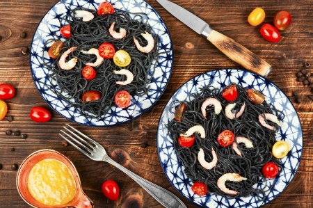 Téléchargez les photos : Spaghettis végétariens aux crevettes et tomates. Spaghettis de pâtes aux crevettes sur fond bois. Vue du dessus. - en image libre de droit