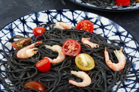 Téléchargez les photos : Spaghettis végétaliens aux crevettes et tomates. Spaghettis aux pâtes noires cuites. - en image libre de droit