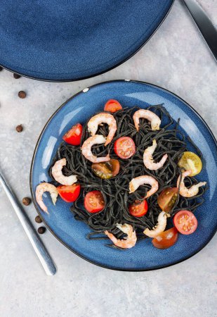 Foto de Espagueti negro vegetariano o pasta con gambas y tomates. Concepto de comida saludable. - Imagen libre de derechos