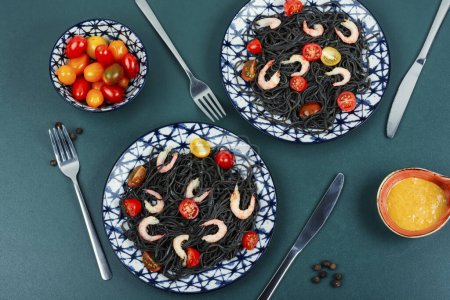 Photo for Vegan black bean spaghetti with shrimp and tomatoes. Cooked black pasta spaghetti on a plate. - Royalty Free Image