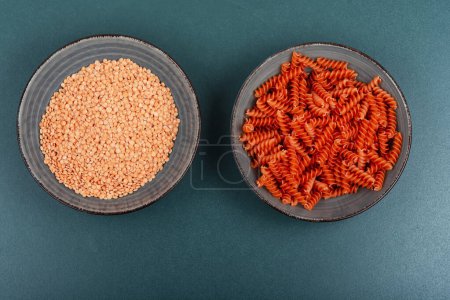 Photo for Uncooked vegan pasta or macaroni, red lentil fusilli on the kitchen table. - Royalty Free Image