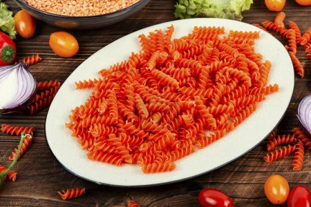 Photo for Uncooked Vegan Pasta, Red Lentil fusilli on the plate. Italy cuisine. - Royalty Free Image