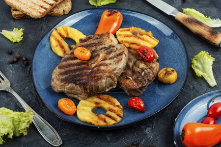 Téléchargez les photos : Viande grillée savoureuse, rôtie à l'ananas. Steak grillé et ananas sur fond de pierre. - en image libre de droit