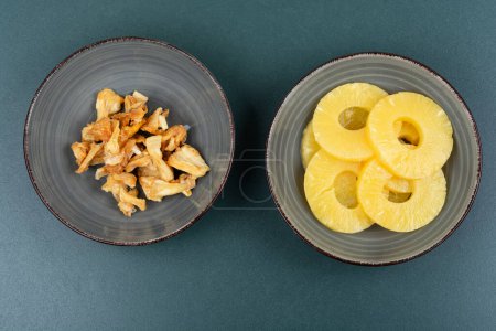 Téléchargez les photos : Ananas secs et frais dans des bols. Ananas aux bonbons, fruits confits. Collation aux fruits. - en image libre de droit