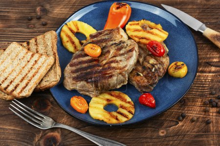 Téléchargez les photos : Viande grillée avec ananas, steak grillé et ananas sur table en bois. - en image libre de droit