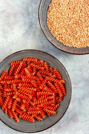 Photo for Raw red lentil fusilli on the plate. Bowl of uncooked red lentil fusilli. Vegan food concept. Top view. - Royalty Free Image