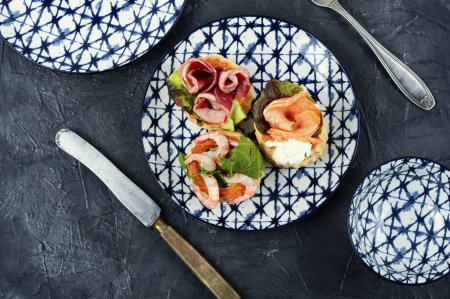 Foto de Tartaletas de hojaldre o canapés con pescado, camarones y tocino en un plato sobre la mesa. - Imagen libre de derechos