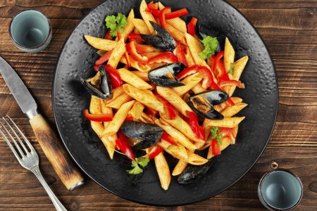 Photo for Macaroni with Atlantic mussels on a dark plate. Pasta with seafood. Noodles with mussels on wooden table. Top view. - Royalty Free Image