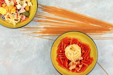 Téléchargez les photos : Un ensemble de macaronis colorés secs, pâtes non cuites et spaghettis. Espace pour le texte. - en image libre de droit