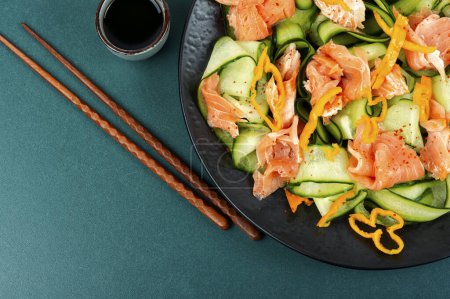 Foto de Ensalada deliciosa con salmón ahumado y pepino fresco. Cocina asiática. Copiar espacio. - Imagen libre de derechos