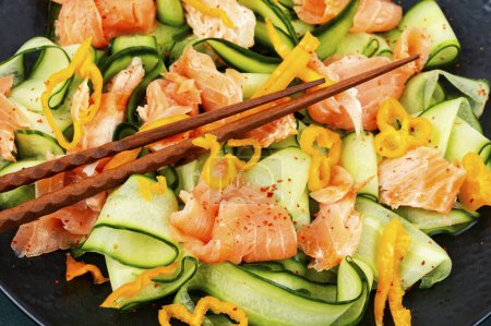 Téléchargez les photos : Salade asiatique épicée avec saumon salé et concombres frais et baguette. Petit déjeuner faible en glucides. - en image libre de droit