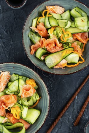 Téléchargez les photos : Salade asiatique au saumon fumé et concombre frais dans un bol. - en image libre de droit