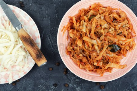 Téléchargez les photos : Chou cuit appétissant dans une assiette. Ragoût maison traditionnel de choucroute sur fond de pierre. - en image libre de droit