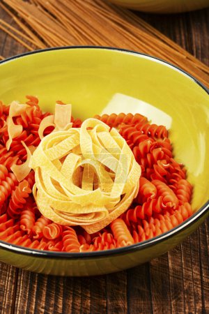 Téléchargez les photos : Différents types et formes de pâtes, nouilles et spaghettis dans un bol. - en image libre de droit