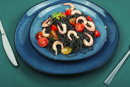 Téléchargez les photos : Pâtes spaghetti végétariennes aux crevettes et tomates. Des pâtes noires. Concept d'alimentation saine. - en image libre de droit