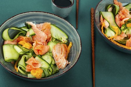Téléchargez les photos : Salade asiatique épicée avec saumon salé et concombres frais. Petit déjeuner faible en glucides. - en image libre de droit