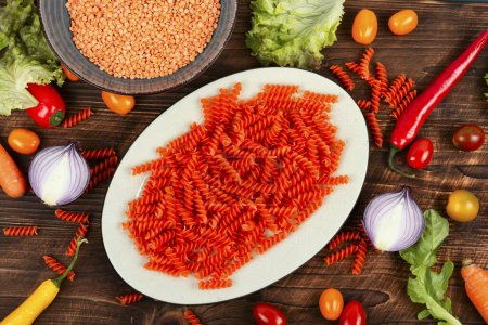 Photo for Uncooked Vegan Pasta, Red Lentil fusilli on the plate. - Royalty Free Image