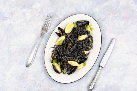 Foto de Pasta de mariscos negros con mejillones cocidos en plato blanco. Vongole de pasta mediterránea. Copiar espacio. - Imagen libre de derechos