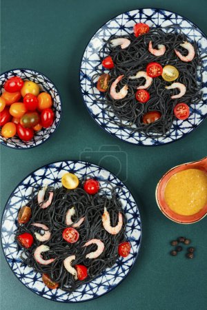 Foto de Espaguetis vegetarianos de frijol negro o pasta con gambas y tomates. Alimentación mediterránea. - Imagen libre de derechos