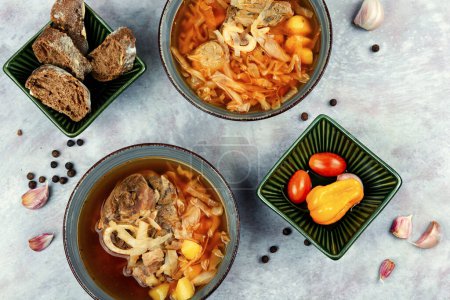 Téléchargez les photos : Bortsch fraîchement cuit, bouillon ou soupe avec de la viande sur la table. Pose plate. - en image libre de droit