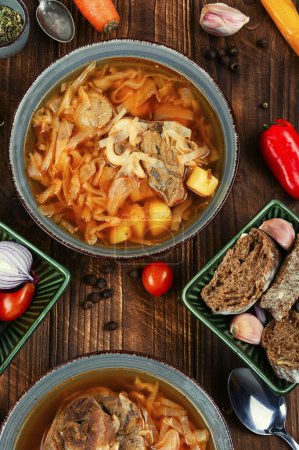 Téléchargez les photos : Soupe à la viande sur une vieille table rustique en bois. Le bortsch ukrainien traditionnel. Recette alimentaire. - en image libre de droit