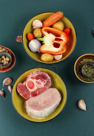 Foto de Carne fresca, cruda y diferentes verduras sobre la mesa en un tazón. Un conjunto de ingredientes para sopa o borscht. - Imagen libre de derechos
