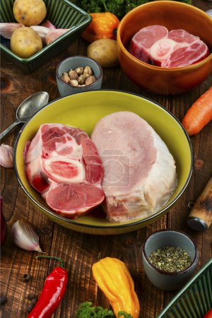 Téléchargez les photos : Viande et légumes crus sur la table de cuisine. Set d'ingrédients pour soupe ou bortsch sur une vieille table rustique en bois. - en image libre de droit