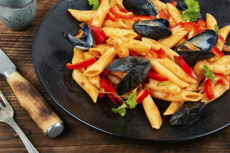 Foto de Macarrones con mejillones servidos en un plato negro. Pastas mediterráneas con mariscos. - Imagen libre de derechos