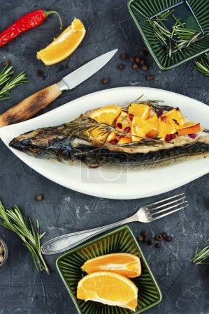 Photo for Appetizing mackerel fish baked with oranges and rosemary served on a stylish plate. - Royalty Free Image