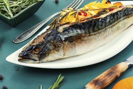 Photo for Appetizing mackerel fish baked with oranges and rosemary served on a stylish plate. Seafood. - Royalty Free Image