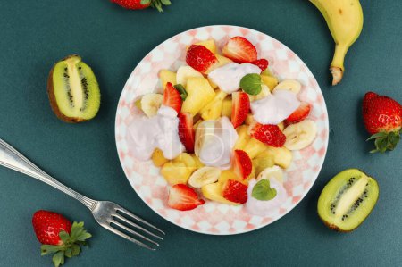 Photo for Fruit salad of pineapple, strawberries,banana, kiwi and sweet yogurt on a plate. Flat lay. - Royalty Free Image