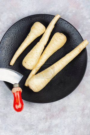 Foto de Raw and uncooked whole parsnips roots on the kitchen table - Imagen libre de derechos