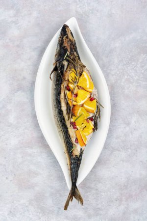 Photo for Whole mackerel fish baked with oranges and rosemary served on a stylish plate. - Royalty Free Image