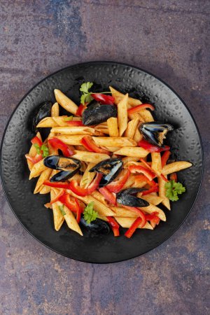 Téléchargez les photos : Macaronis ou pâtes vongole avec des moules dans la coquille, palourdes sur une assiette sombre élégant. Cuisine méditerranéenne. - en image libre de droit