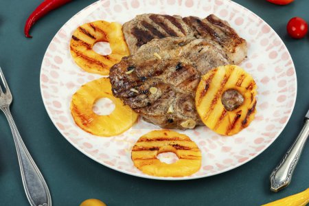 Téléchargez les photos : Steak grillé juteux et ananas. Délicieux steak de porc rôti juteux avec ananas anneaux. - en image libre de droit